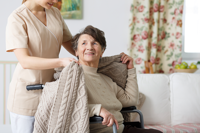 Caregiver covering senior woman with a blanket 