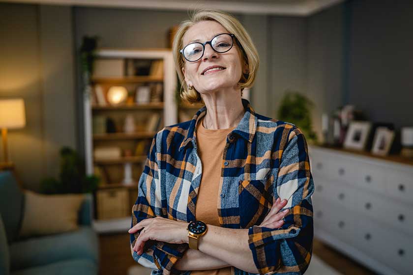 Portrait of one mature blonde caucasian woman with eyeglasses at home happy smile looking to the camera confident wear shirt copy space