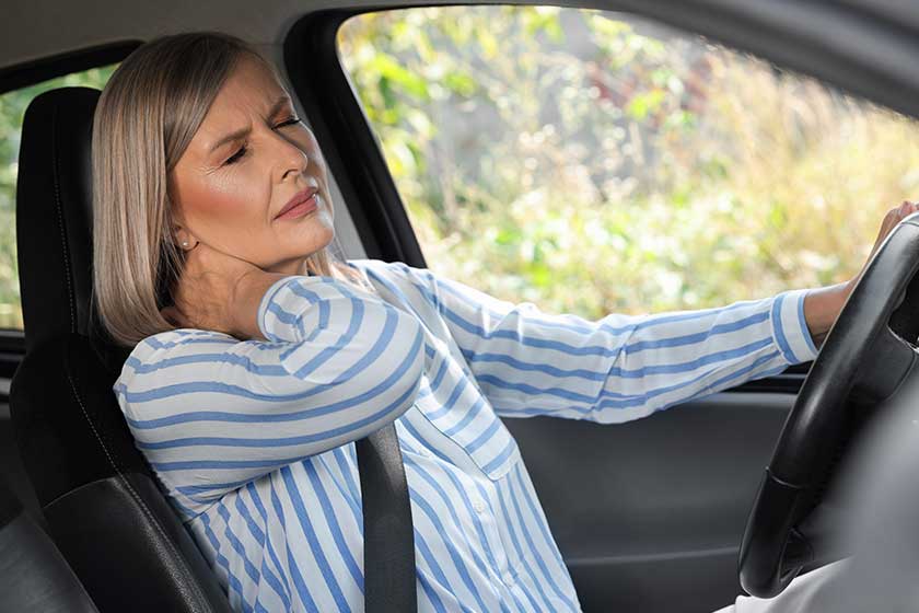 Woman suffering from neck pain in car